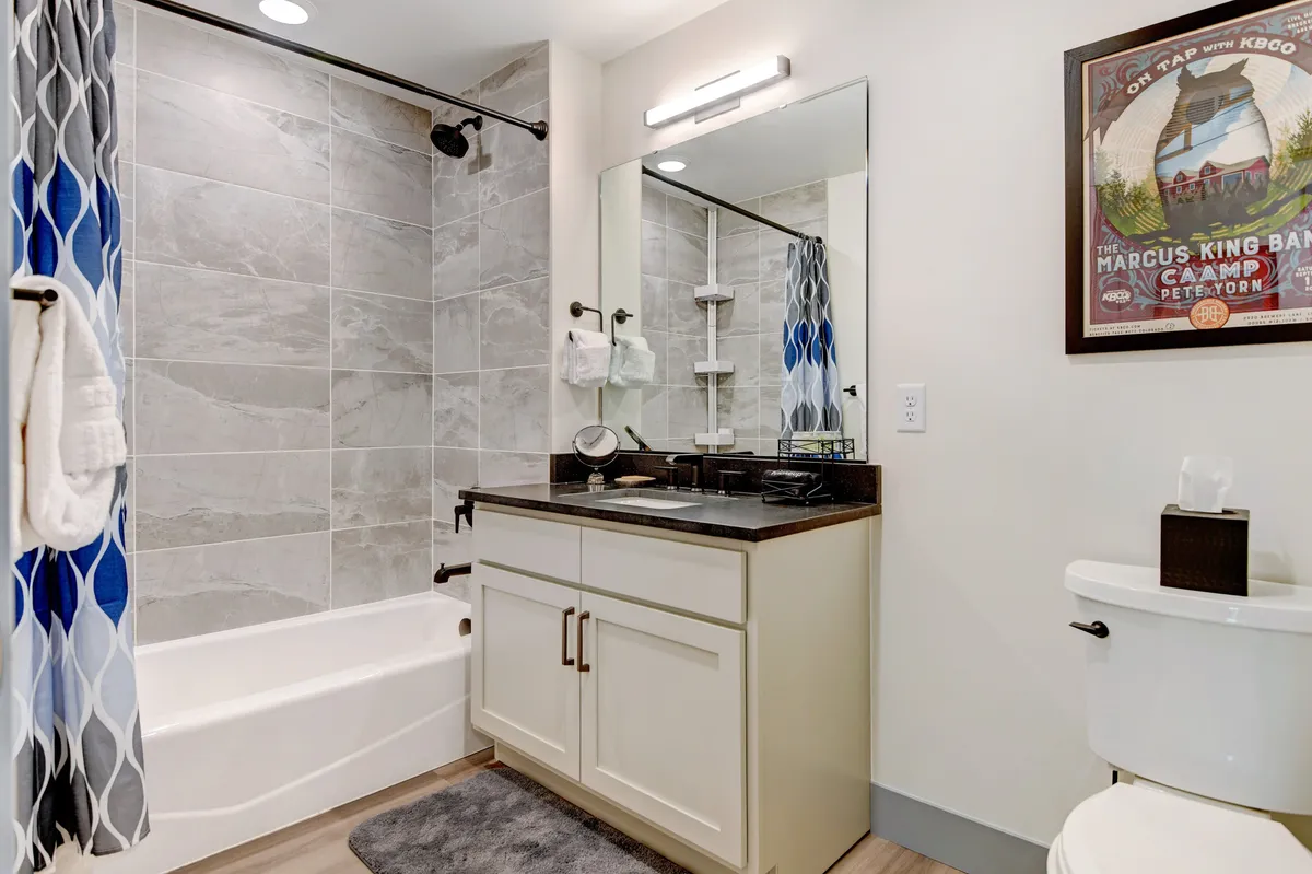 A bright and inviting hall bathroom featuring a full tub/shower combo, vanity with sink and mirror, and cheerful decorative touches. The setup is practical, family-friendly, and perfect for easy access from the bedrooms.