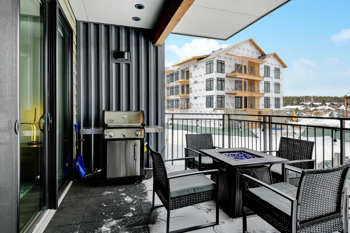 This image highlights a private outdoor patio area featuring a BBQ gas grill, comfortable seating, and a decorative fire pit. The setting evokes a cozy, communal atmosphere ideal for barbecues and relaxed evenings spent outside, whether in summer or winter.